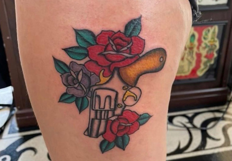 Picture, of a tattoo by Troy, tattoo artist at Top Hat Tattoo, Seattle, of roses and gun
