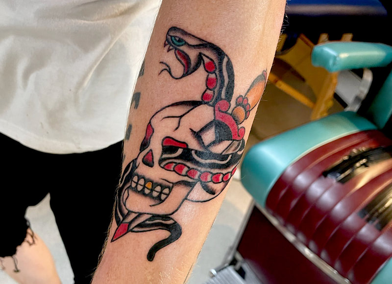 Picture, of a tattoo by Troy, tattoo artist at Top Hat Tattoo, Seattle,  skull with a snake and dagger going through it