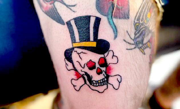 Picture, of a tattoo by Troy, tattoo artist at Top Hat Tattoo, Seattle, skull wearing a top hat with cross bones behind it.