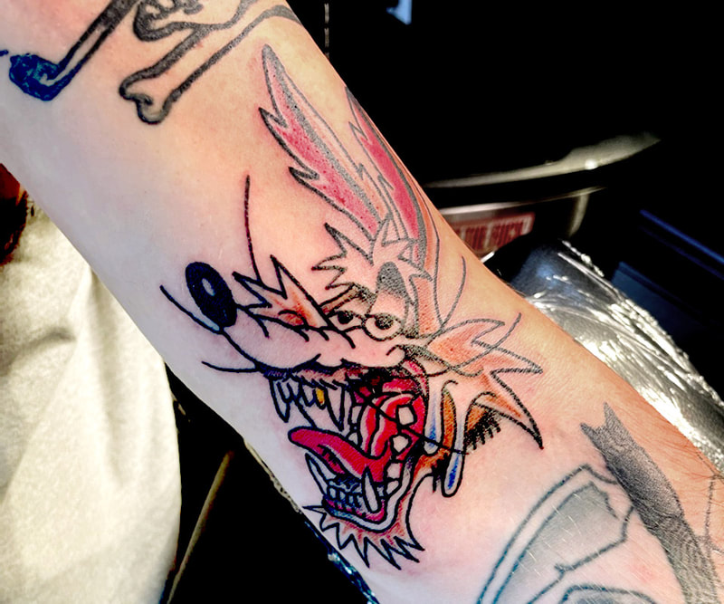 Picture, of a tattoo by Troy, tattoo artist at Top Hat Tattoo, Seattle, wile e coyote from loony toons, with his mouth open and teeth and tongue showing.